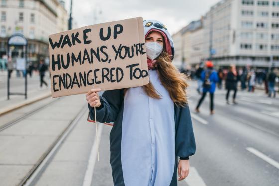 Demonstrant med et skilt hvor det står at mennesker også er utrydningstruet. 