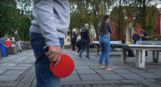 Mann med olabukse, som holder rød bordtennisracket.