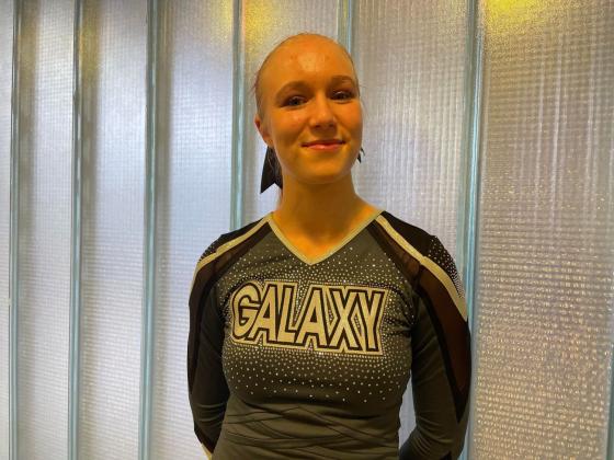 Smilende blond jente i svart cheerleaderdrakt