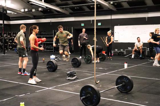 Utøvere som trener Crossfit. En hopper over vektstanga. 