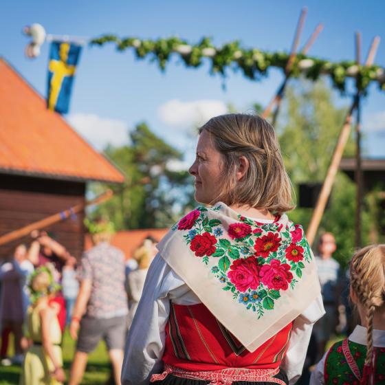 En dame i svensk folkedrakt gjør seg klar for midtsommerfeiring i Sverige.