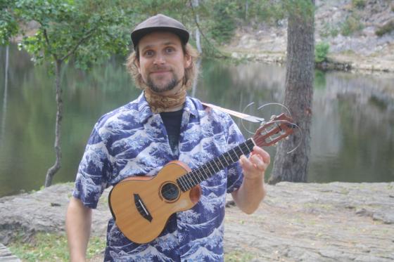 Danny Ukulele med ukulele ved vannet.