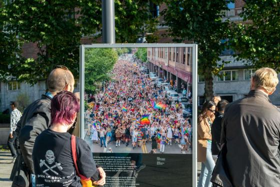 Folk står og ser på et bilde av pride parade