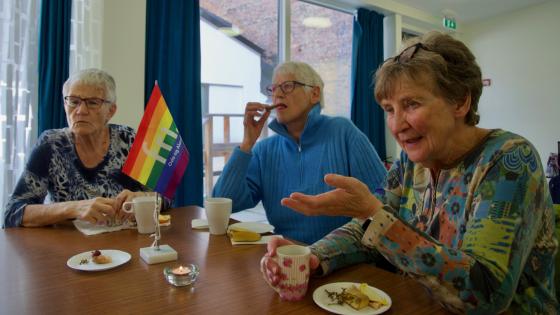 Damer som sitter rundt et bord på Regnbuetreff for senior