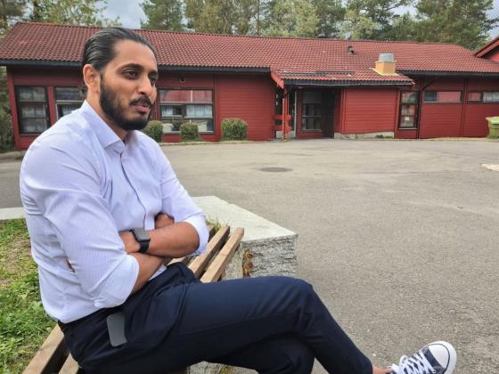 Ap-politiker Farukh Qureshi sitter på en benk utenfor Bjørndal skole.