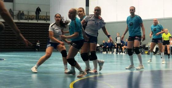 Håndballspillere i kamp med blå bakgrunn