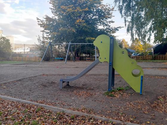 Lekeplassen til Gamlebyen barnehage. Bilde viser en sklie og to husker i bakgrunnen.