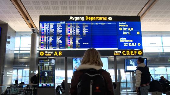 En jente står foran en skjerm på Gardemoen og ser på gatetidene