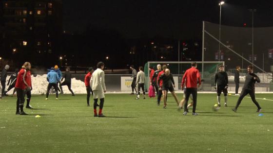 Flere menn løper rundt på en fotballbane. 