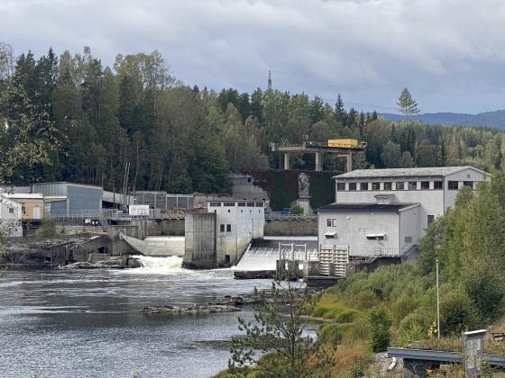 Avstandsbilde av Hellefoss elvekraftverk som viser vannfallet fra kraftstasjonen