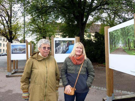 Bilde av to kvinner foran en fotoutstilling ute i en park 