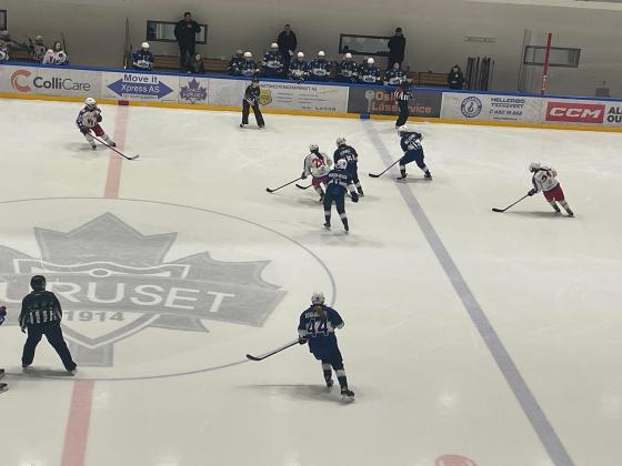 Spillere fra Vålrenga og Furuset spiller ishockey på banen. Spillerne er i bevegelse med ishockeykøller i hånda mens de sender pucken frem og tilbake