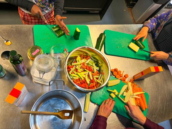 To barn står ved kjøkkenbenket og skjærer grønnsaker sammen med en voksen, FotO: Kiana Hassani