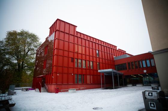 Sofienberg skole fotografert i under en grå himmel. Bygget er farget i en sterk rødfarge. Skolegården er å se i forgrunnen av bildet.