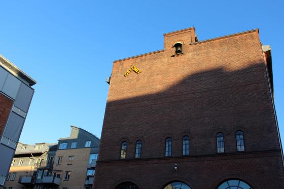 Solen skinner på toppen av et bygg. På bygget er det en gul logo der det står "Oslomet".