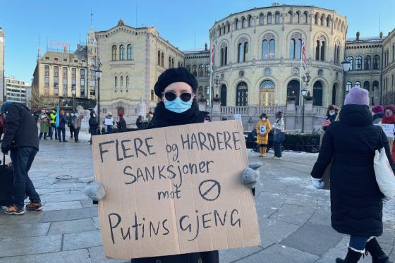 Demonstrant holder et skilt med ordene "flere og hardere sanksjoner mot Putins gjeng" utenfor Stortinget