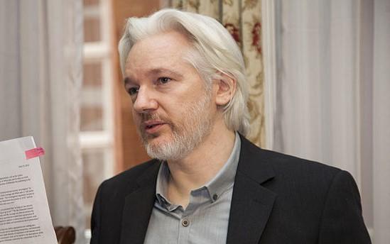 Den australske varsleren og journalisten Julian Assange holder opp et dokument. 