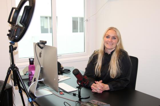 Kvinne med blond hår sitter ved bordet på kontoret. 