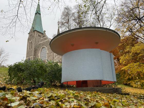 Kjærlighetskarusellen står nedenfor en kirke i Stensparken, til høyre i bildet. Det lyser fra bygget.  