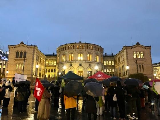 Demonstranter med paraplyer foran Stortinget