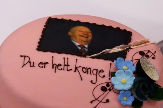 En rosa kake med bilde av kong Harald på. Teksten under står det "Du er helt konge"