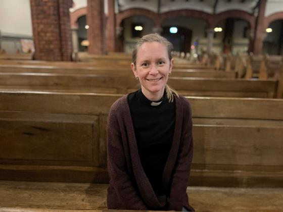 Krisitn Heskje, prest i Uranienborg kirke sitter smilende i kirkebenken i Uranienborg kirke.