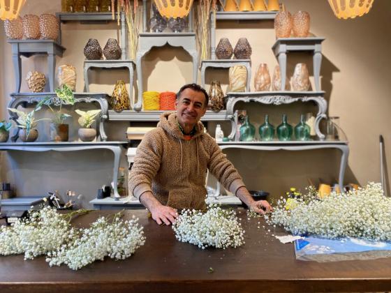 Mahmut Aydın star bak kassen i butikken Blomsterista og binder buketter.