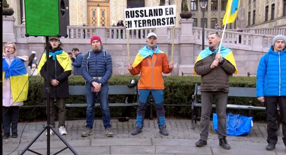 En mann med skilt som sier "Russland er en terrorstat"