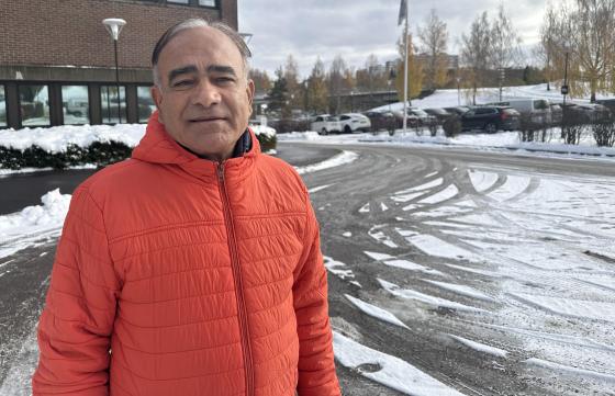 Ombir Singh Upadhyay står i en oransje jakke utenfor et bygg på Stovner i Oslo. 