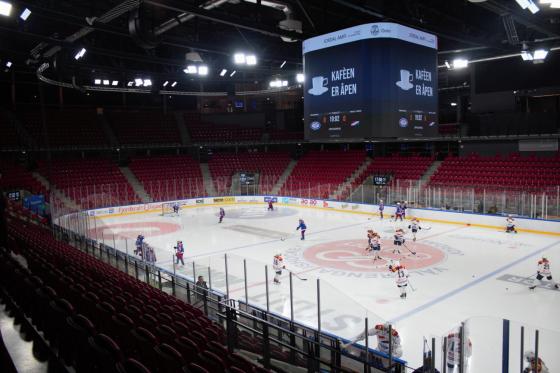 En ishockeybane omringet av røde tribune stoler. Det er 11 Vålerenga spillere og 10 Hasle 