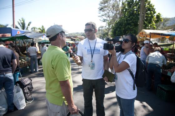 To journalister intervjuer en mann på et travelt marked i Costa Rica. 