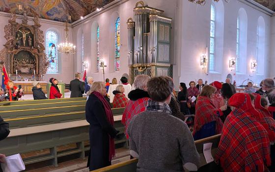 folk ser på et følge som går inn midtgangen i Oslo domkirke