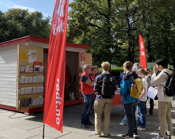 Rødt sin stand plassert i Karl Johan. Flagg fra Rødt i forgrunnen. Ungdommer står rundt.