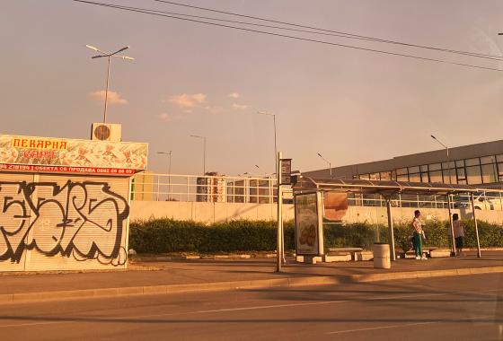 En gate i Bulgaria om sommeren. Det er kun to mennesker på busstoppet.