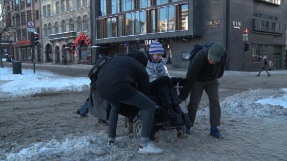 rullestol sitter fast i snø i Oslo, to personer hjelper