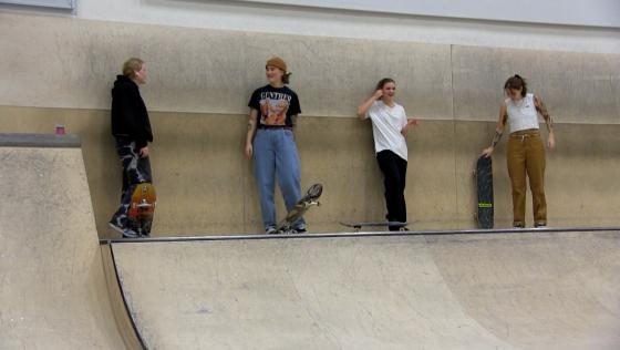 Marte Gundersen og Tiril Melby står sammen med andre jenteskatere i Oslo Skatehall