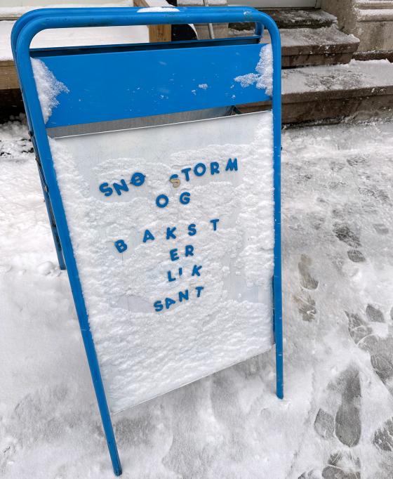 Et skilt utenfor en kafe der det står at snøstorm og bakst erlik sant