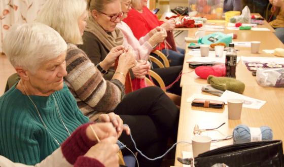 En rekke med damer som sitter og strikker