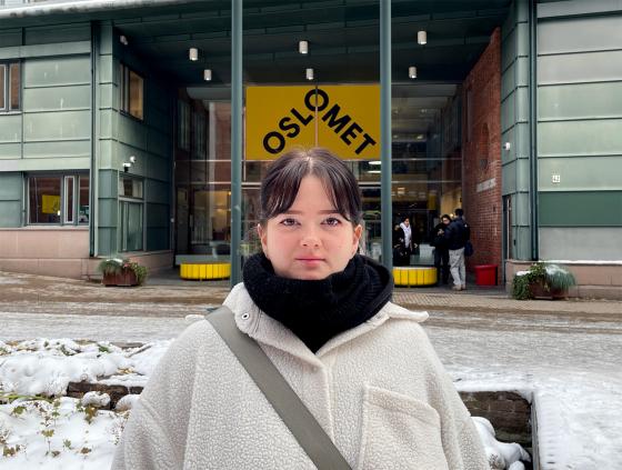 En student står ute på campus på OsloMet. 