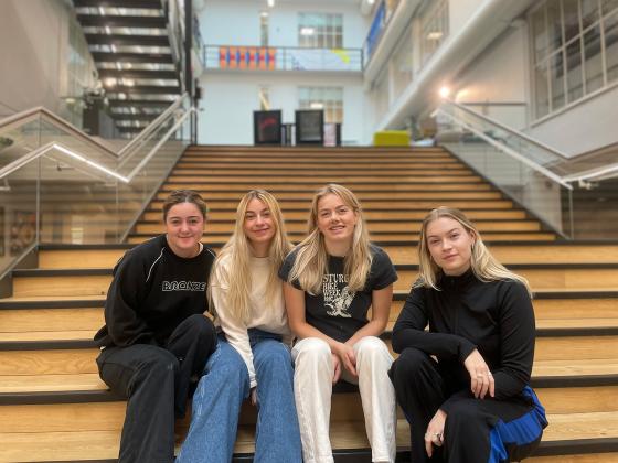 Fire jenter sitter I trappa på Høyskolen Kristiania.