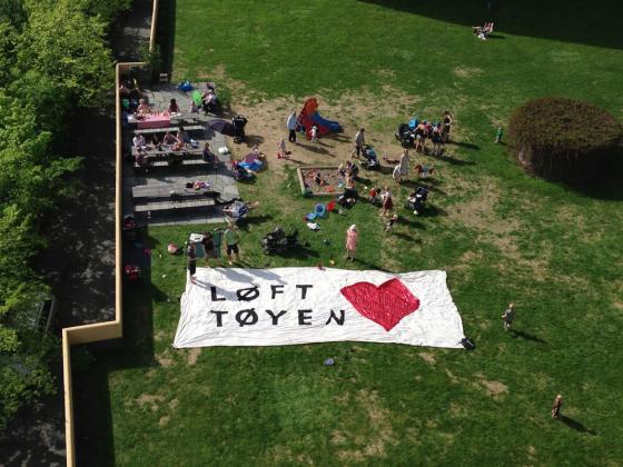 En gruppe mennesker markerer med et flagg med teksten "Løft Tøyen". 