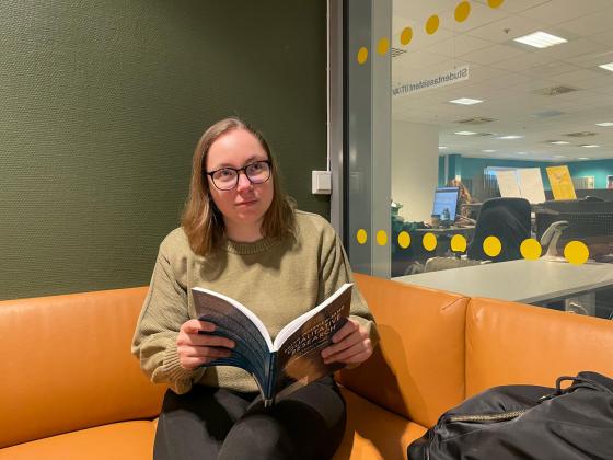 Dafne Henningsen (28) sitter med boken sin og leser. 