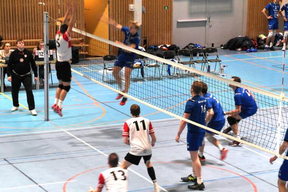 En spiller fra BK Tromsø smasher en volleyball forbi en spiller fra OSI som prøver å blokke.