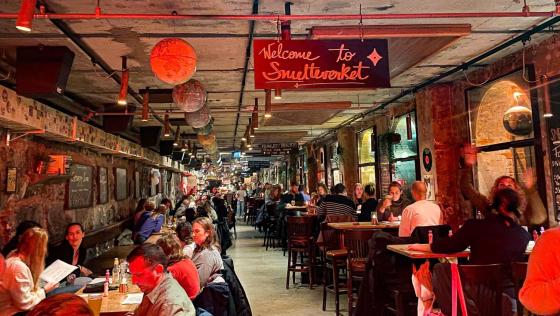 Smelteverket er et sted folk kommer til å være med på musikkbingo. På bildet ser vi mange grupper folk som sitter ved deres bord og prater med hverandre. 