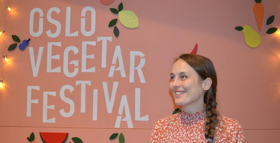 Ung kvinne står foran Oslo Vegetarfestival-skilt og smiler