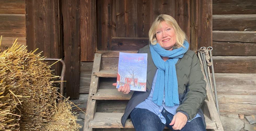 Dame som sitter på en trapp, hun holder et magasin som heter Sagenejul. Bildet er tatt på Vøienvolden gård. 