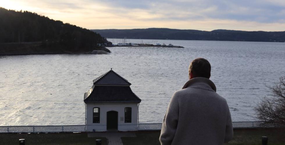 Arild Berg står på toppen av en bakke, nedenfor er det et hus.