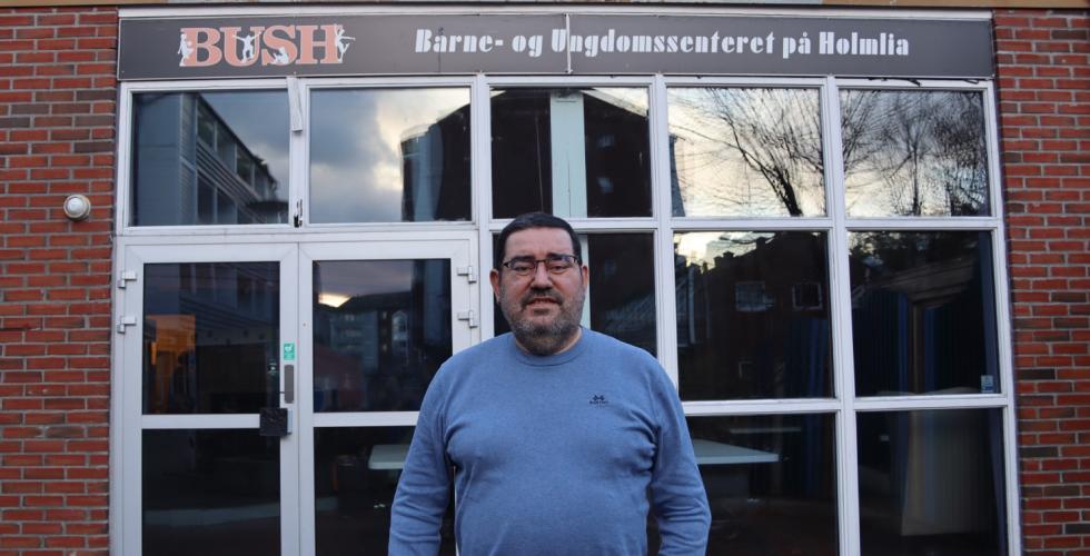 Klubblederen i blå genser foran logoen til BUSH