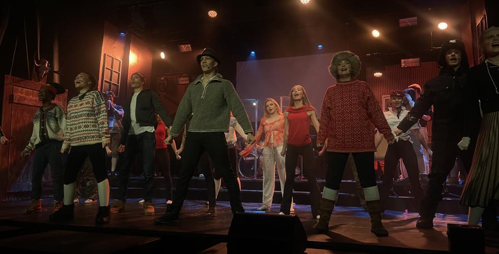 En scene med videregående elever i kostymer som synger og danser