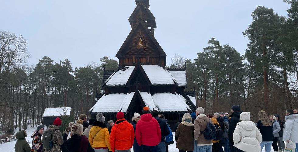 En stavkirke med en mengde mennesker rundt. De er på omvisning.